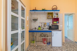 A compact kitchen with a microwave, sink, and storage shelves.