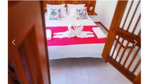 Cozy retreat with a neatly made bed, featuring a bedspread and a vibrant blanket, and adorned with towels and pillows.