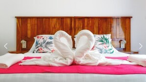 Un lit avec une tête de lit en bois, des coussins à motifs floraux et une couvre-lit rouge.