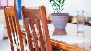 Une table à manger en bois, avec des chaises et une plante en pot.