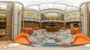 A spacious lobby with a checkered carpet, orange seating, a bar area, and a high ceiling with skylights. - Golden Tulip Jalandhar (Jalandhar)