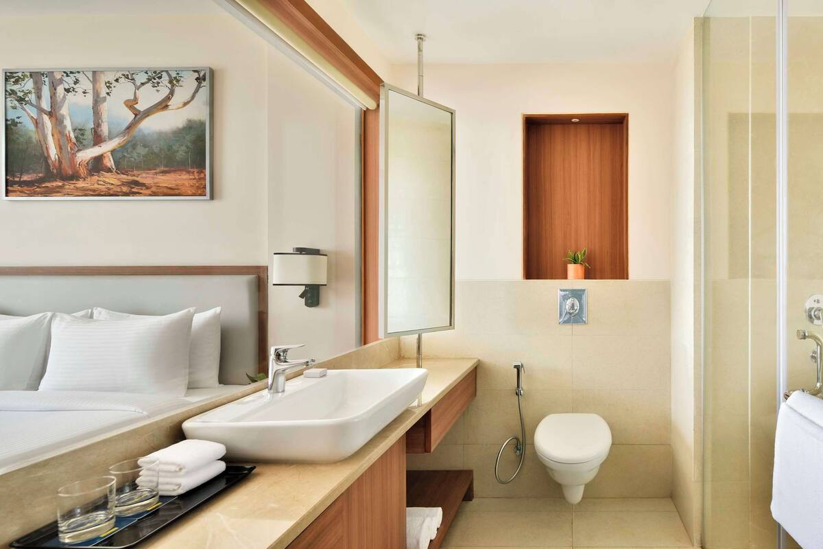 Ein Hotelbad mit einem großen Bett, einem Waschbecken, einer Toilette und einer Dusche.