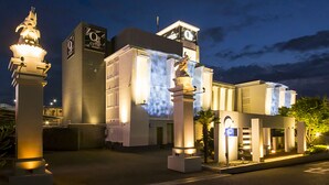 Entrada de hotel con diseño moderno, destacando un letrero llamativo y pilares iluminados.