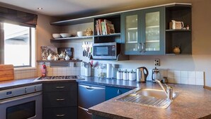 Una cocina moderna con encimera de granito, electrodomésticos de acero inoxidable y armarios azules.