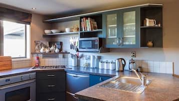 Une cuisine moderne dotée d’un comptoir en granit, d’appareils électroménagers en acier inoxydable et de meubles de couleur bleue.