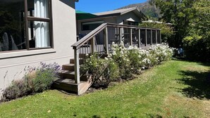 Una casa moderna con terraza de madera, ventanas amplias y un jardín bien cuidado.