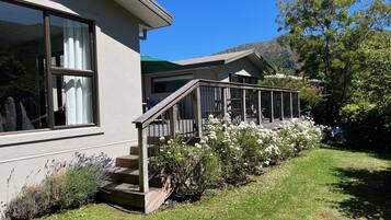 A modern house with a wooden deck, large windows, and a well-maintained garden.