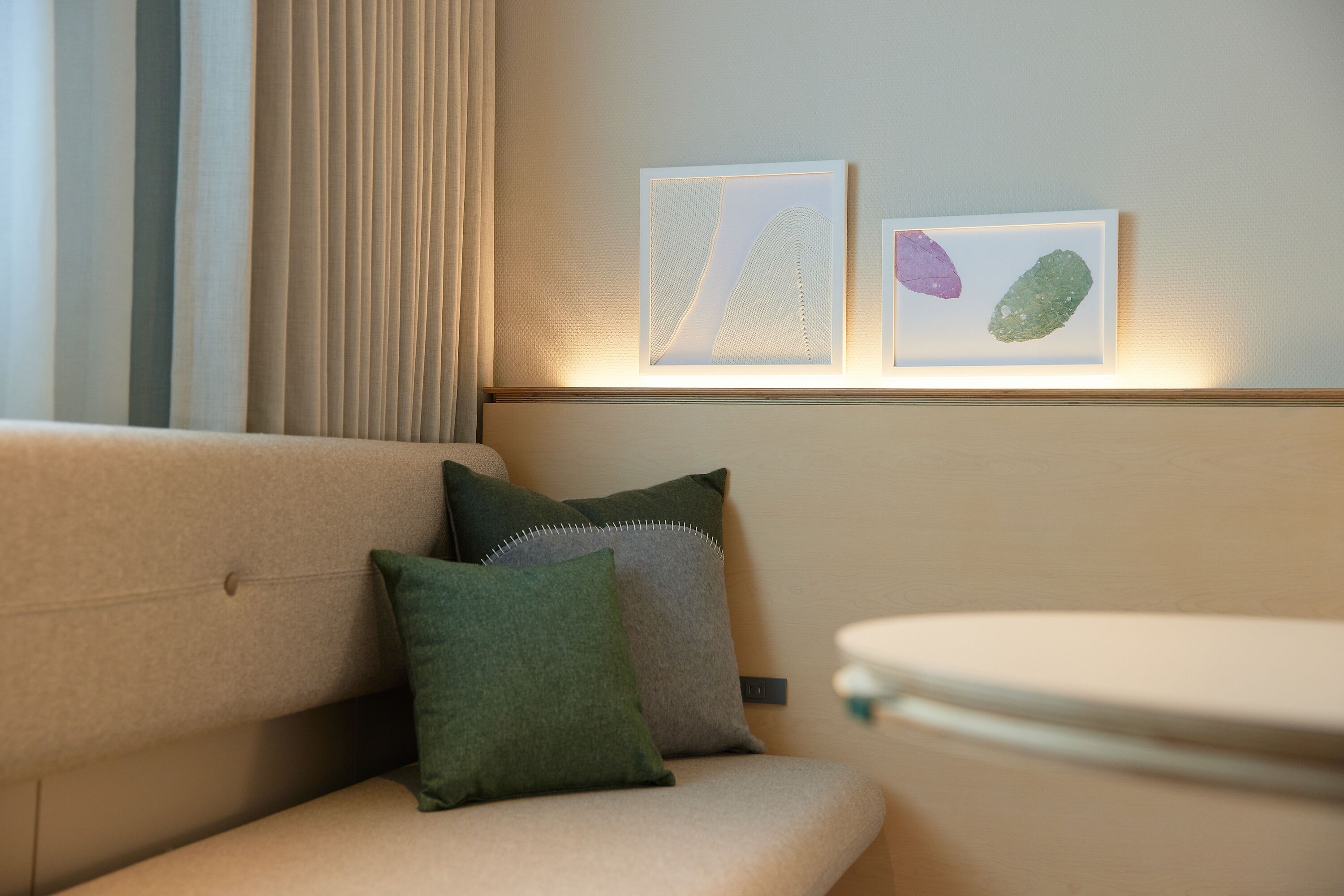 A modern living room with a beige sofa, two cushions, and a small table.
