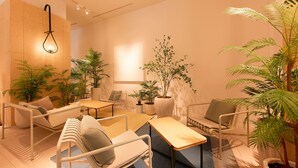 A modern lounge area with seating, tables, and potted plants. - Keikyu EX Hotel Sapporo (Sapporo)