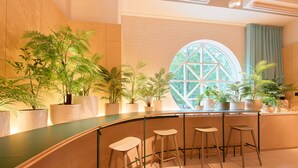 A bar area with a curved counter, four stools, and potted plants. - Keikyu EX Hotel Sapporo (Sapporo)