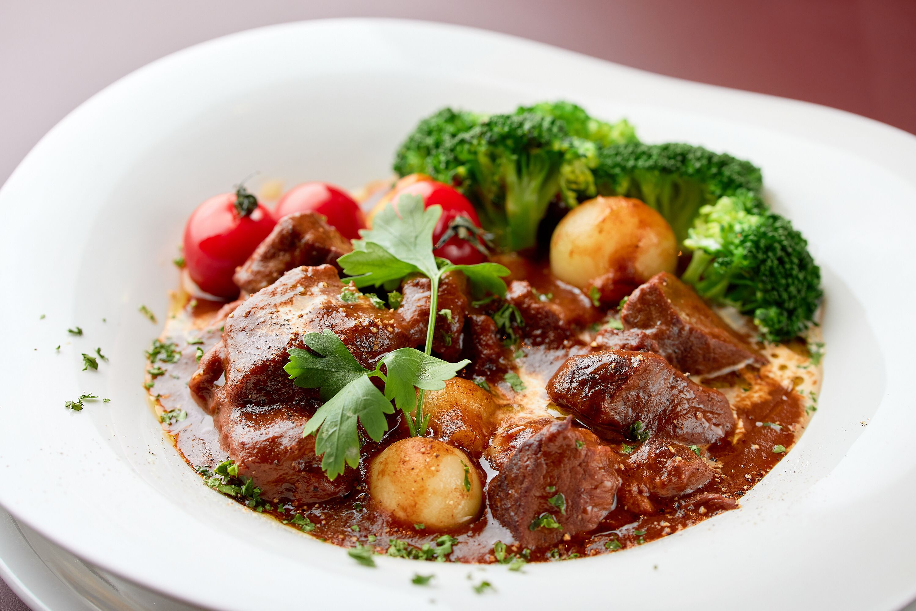 A dish with beef, potatoes, and broccoli on a white plate.