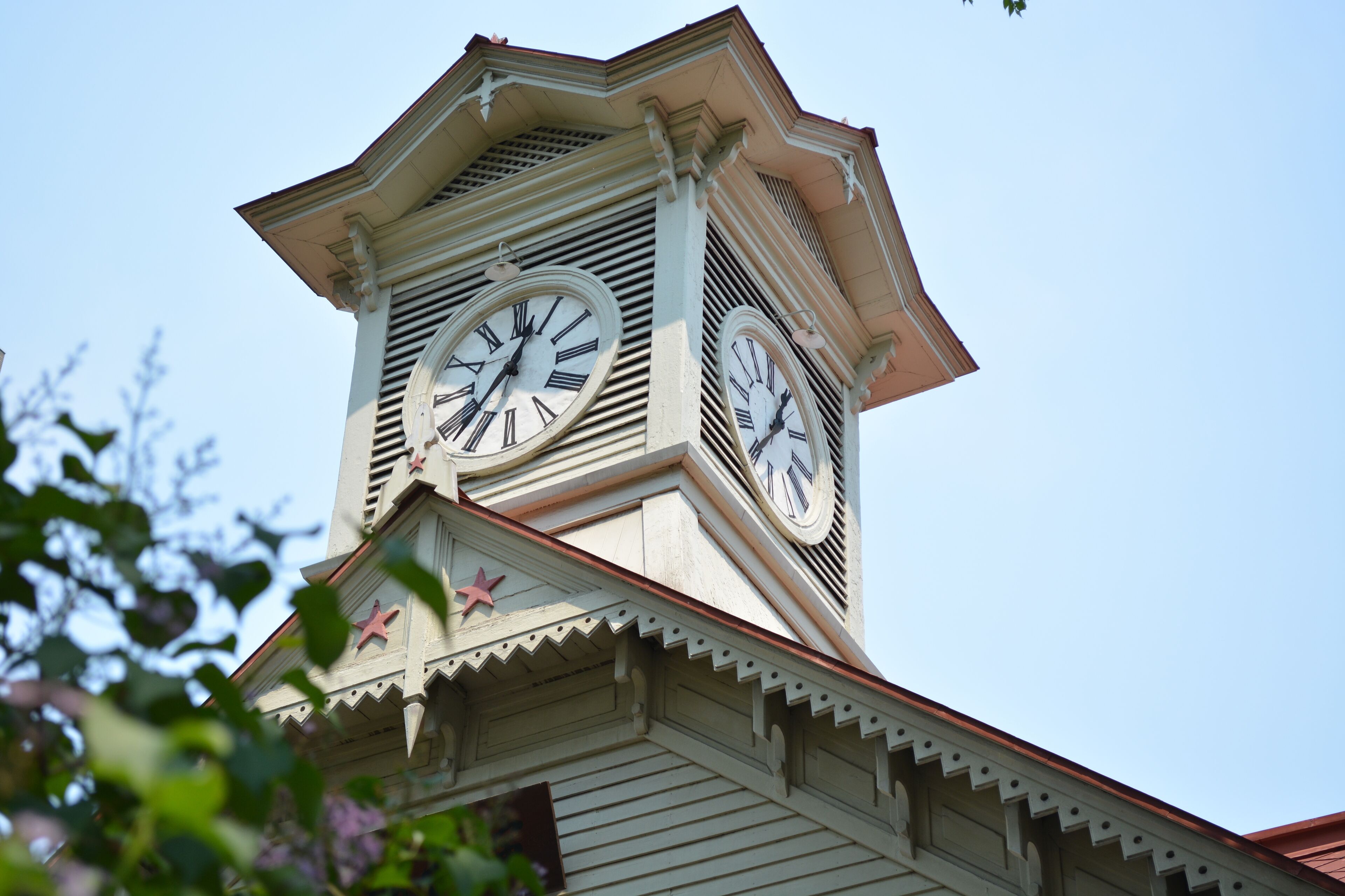 A clock tower with two large clocks, a star decoration, and a clear sky in the background.