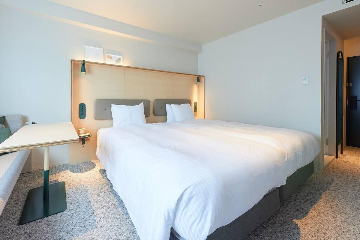 A hotel room with a bed, a desk, a chair, and a sofa.