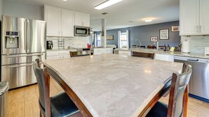 A modern kitchen with stainless steel appliances, white cabinetry, and a large marble island.