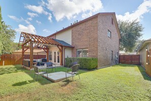 Een achtertuin met terras, zitgedeelte en een houten pergola.