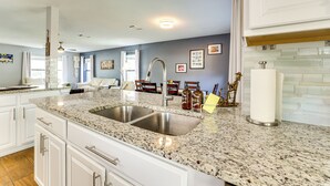 A kitchen with granite countertops, stainless steel sink, white cabinetry, and a backsplash with white subway tiles.