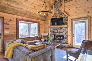 L’intérieur d’un chalet confortable, avec une cheminée en pierre, des murs en bois et un coin salon accueillant.