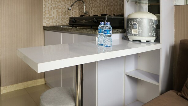 A compact kitchen with a white countertop, a water dispenser, and a rice cooker. - Homey And Cozy Stay 2Br At Green Pramuka City Apartment (Jakarta)