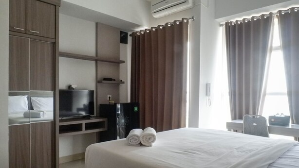 A hotel room with a bed, a TV, a desk, and a wardrobe. - Exclusive And Comfy Studio Room Apartment At Taman Melati Surabaya (Surabaya)