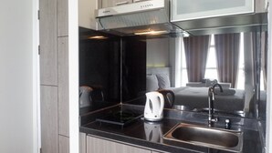 A modern kitchen with a black countertop, stainless steel sink, and a white electric kettle. - Exclusive And Comfy Studio Room Apartment At Taman Melati Surabaya (Surabaya)