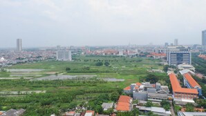 A cityscape with a mix of residential and commercial buildings, including a prominent high-rise and a large building with a red roof. - Exclusive And Comfy Studio Room Apartment At Taman Melati Surabaya (Surabaya)