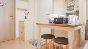 A small kitchenette with a coffee maker, a kettle, and a box labeled "Levallino". There are two stools and a small table. - Comfort 1Br With Working Room At Meikarta Apartment (Cikarang)