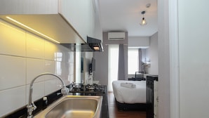 A compact hotel room with a kitchenette, a bed, and a small sitting area. - Fancy And Nice Studio Apartment At Springlake Summarecon Bekasi (Bekasi)
