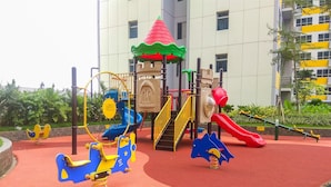 Ein Spielplatz mit Rutsche, Schaukeln und einer Kletterkonstruktion.