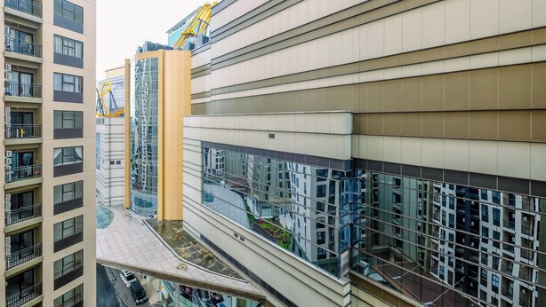 Un edificio moderno con diversi piani, ampie finestre e una gru da cantiere ben visibile.