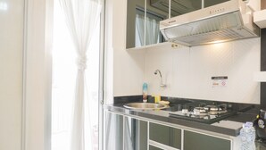 A modern kitchen with a stainless steel sink, a gas stove, and a built-in range hood. - Comfort Living And Minimalist 1Br At Bassura City Apartment (Jakarta)