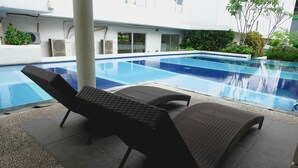 A swimming pool with lounge chairs and a tiled deck area. - Comfort Living And Minimalist 1Br At Bassura City Apartment (Jakarta)