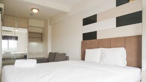 A modern hotel room with a large bed, a bedside table, a mirror, and a built-in wardrobe. - Comfort Living And Minimalist 1Br At Bassura City Apartment (Jakarta)