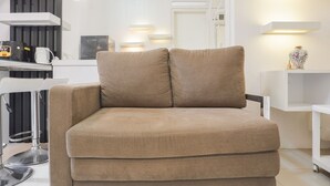 A modern living room with a beige sofa, a coffee machine, and a white TV stand. - Comfort Living And Minimalist 1Br At Bassura City Apartment (Jakarta)
