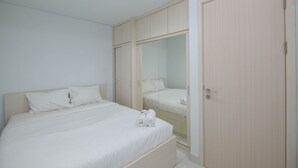 A bedroom with a bed, a wardrobe, and a mirror. - Comfy And Homey 2Br At Patraland Urbano Apartment (Bekasi)