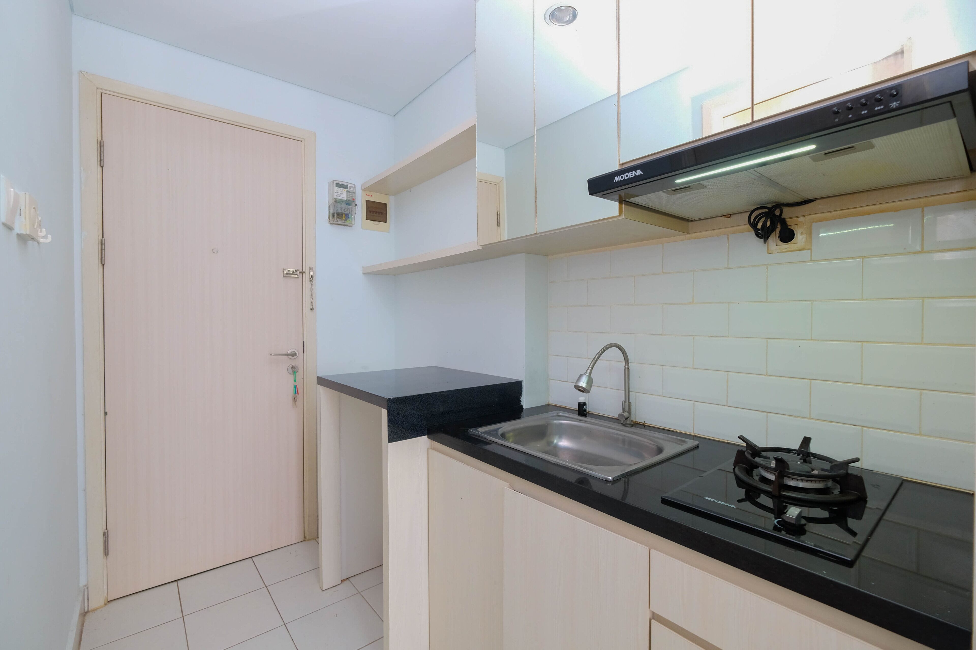 A compact kitchen with a black countertop, stainless steel sink, and a gas stove.