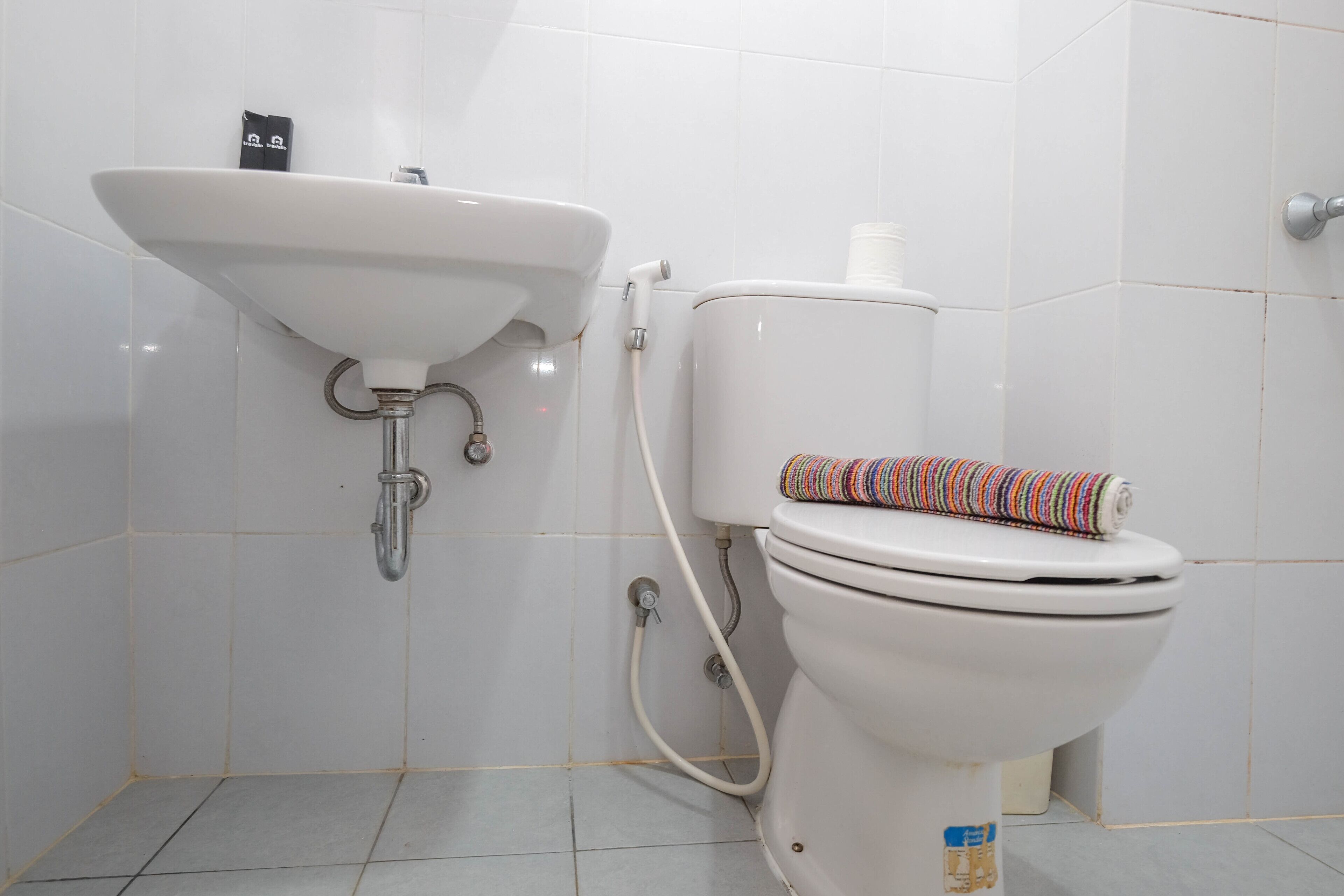 Un baño con lavamanos blanco, inodoro y paredes con azulejos.