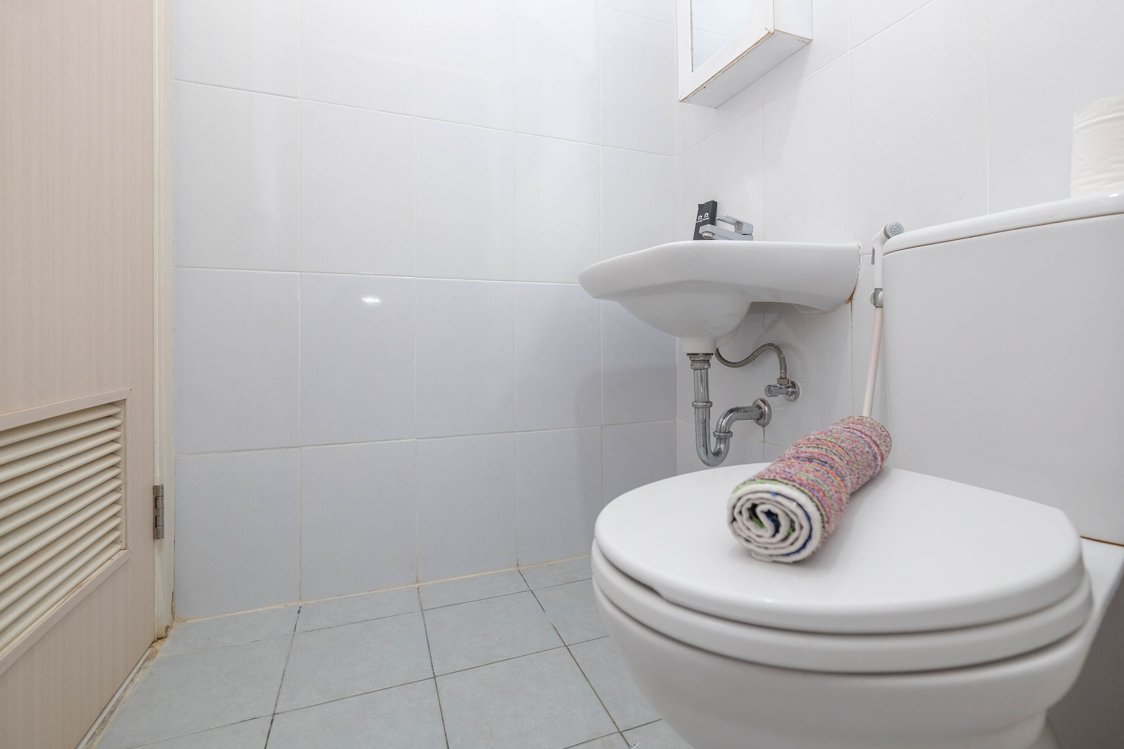 A bathroom with a white toilet, a sink, and a tiled floor.