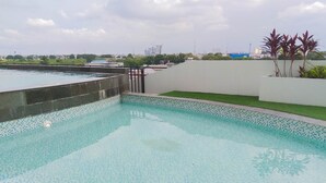 A swimming pool with a tiled edge and a grassy area beside it.