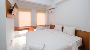 A hotel room with a bed, a desk, an air conditioner, and a TV mounted on the wall.