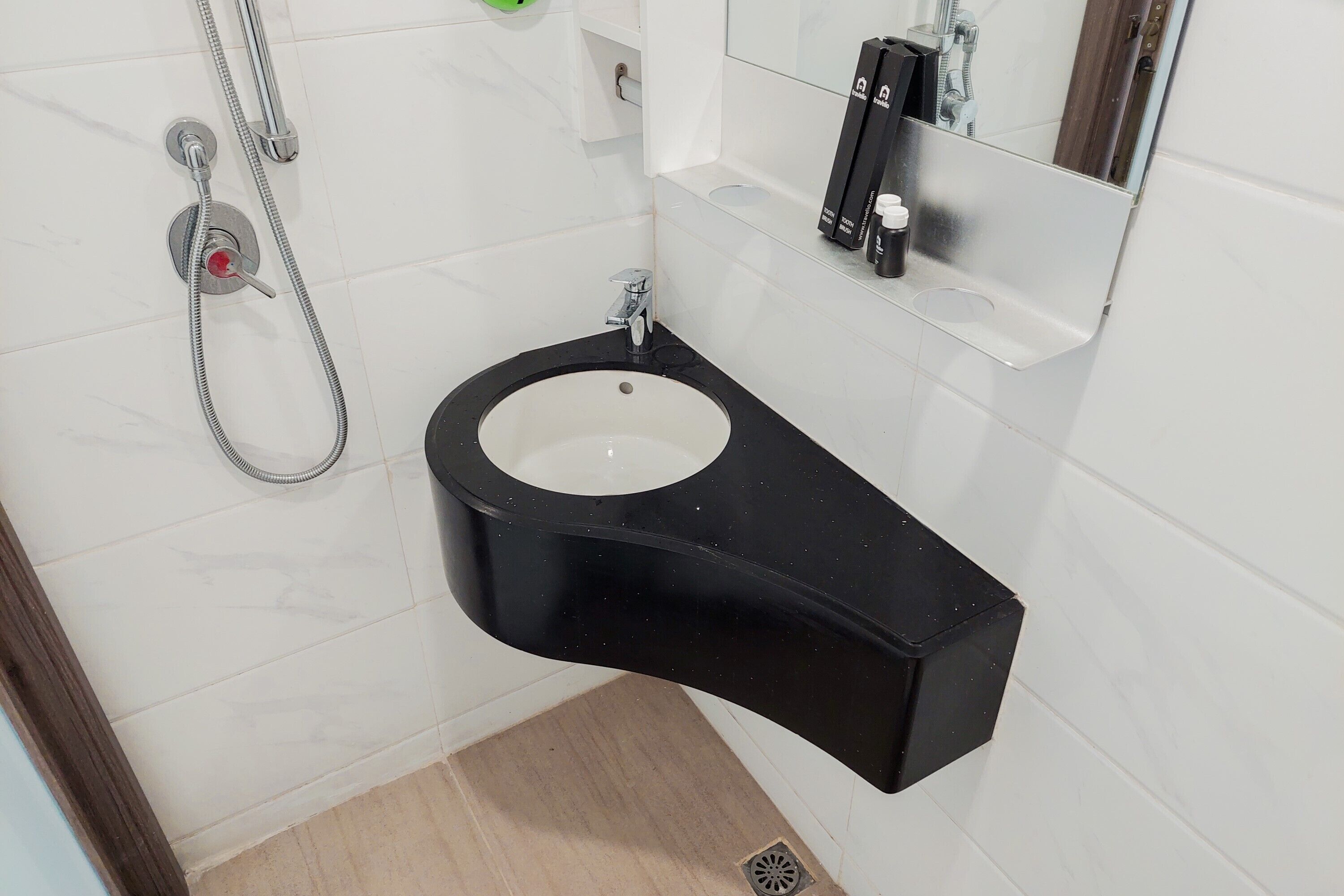 A bathroom with a black sink, white tiles, a mirror, and a shower head.