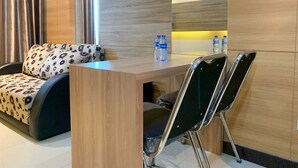 Un espace de vie moderne et compact, comprenant un canapé, une petite table à manger et deux chaises.