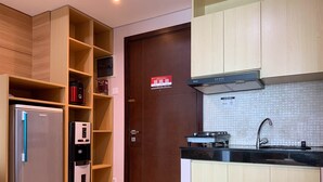 Une cuisine compacte dotée d’un réfrigérateur encastré, d’une cuisinière et d’étagères en bois.