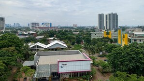 Une vue urbaine mêlant bâtiments modernes et traditionnels, avec notamment une imposante structure jaune et plusieurs gratte-ciel en arrière-plan.