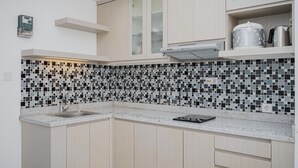 A modern kitchen with a tiled backsplash, a built-in microwave, and a coffee maker on the countertop. - Modern Look And Comfy 2Br At Casa De Parco Apartment (Pagedangan)