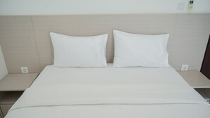 A neatly made bed with white bedding and pillows, a wooden headboard, and bedside tables with power outlets. - Modern Look And Comfy 2Br At Casa De Parco Apartment (Pagedangan)