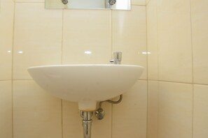 A bathroom with a white sink mounted on a tiled wall. - Cozy And Strategic Studio At Bassura City Apartment (Jakarta)