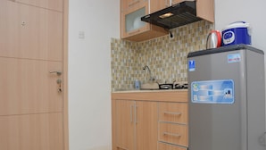 A kitchen with wooden cabinets, a stainless steel refrigerator, and a tiled backsplash. - Cozy And Strategic Studio At Bassura City Apartment (Jakarta)