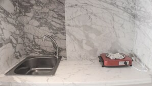 A kitchen with a stainless steel sink and a red electric stove. - Warm And Cozy Studio At Springlake Summarecon Apartment (Bekasi)