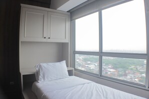 A bedroom with a bed, a window, and a white wardrobe. - Warm And Cozy Studio At Springlake Summarecon Apartment (Bekasi)