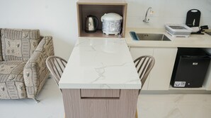 A compact kitchen with a marble countertop, a built-in oven, a sink, and a dishwasher. - Homey And Cozy Living 2Br At Sky House Bsd Apartment (Pagedangan)